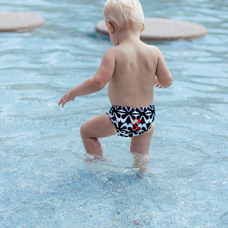 child wearing swim diapers, showing embroidered logo on back